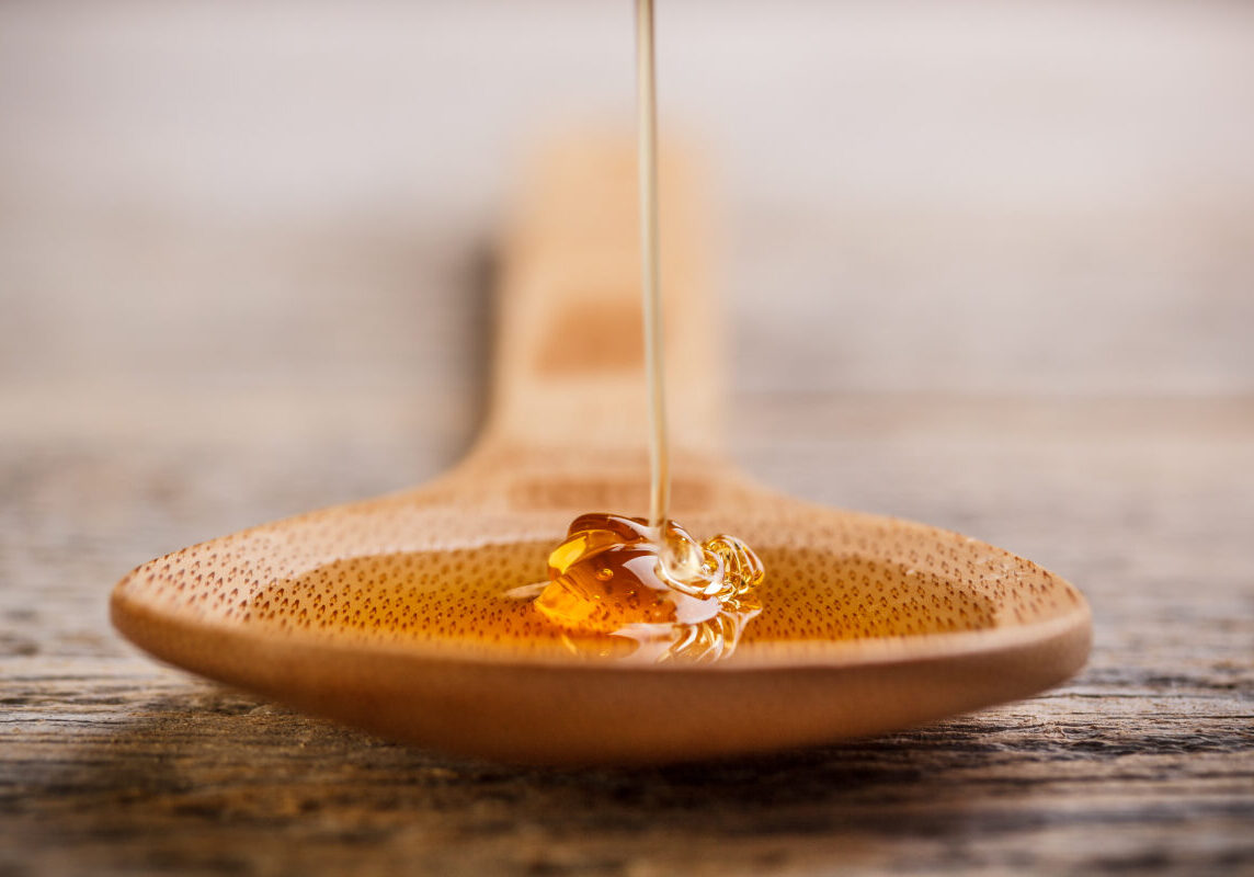 Wooden spoon with wild honey falling into it